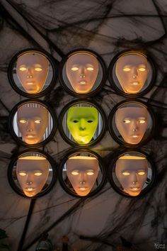 many faces are shown in the center of a circular mirror with lights on it and behind them there is a yellow mask