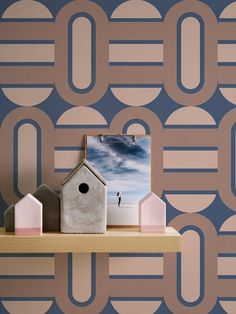 a birdhouse on a shelf in front of a wallpapered background with circles