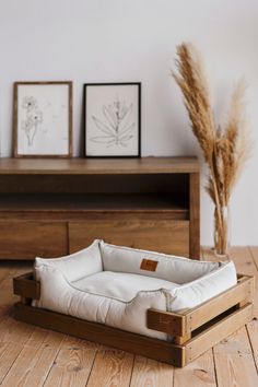 a dog bed is sitting on the floor next to a vase with dry grass in it