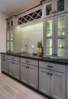 a kitchen with gray cabinets and black counter tops in the center is an empty dining room