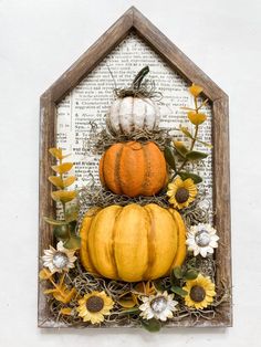 a wooden frame with pumpkins and sunflowers on it