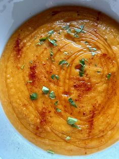 a white bowl filled with soup and garnished with parsley on the top