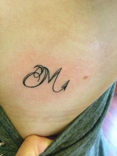 a woman's lower back tattoo with the letter m on her left ribcage