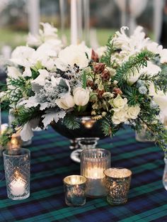 the centerpiece is surrounded by white flowers and greenery, with votive candles