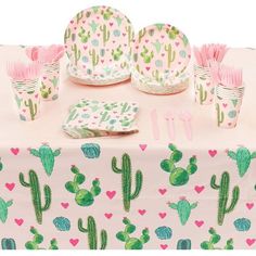 a table topped with lots of pink and green cactus themed paper plates, cups and utensils