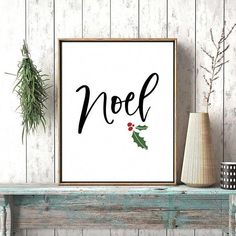 a poster with the word noel on it next to a vase and potted plant