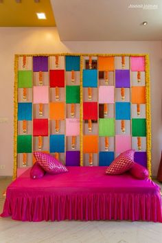 a bed with colorful pillows on top of it in front of a wall made out of colored blocks