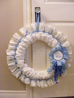 a white and blue wreath hanging on the front door with a name tag attached to it