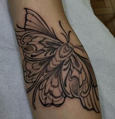 a black and white butterfly tattoo on the right arm, it looks like an intricate piece of art