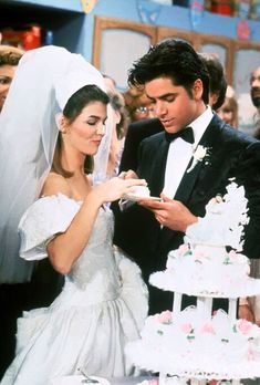 the bride and groom are cutting their wedding cake at the table in front of other people