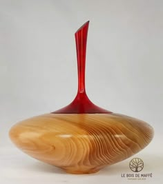 a red vase sitting on top of a wooden bowl