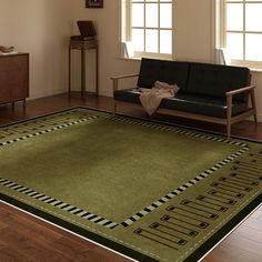 a living room with a black couch and green rug