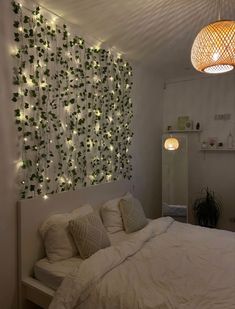 a bedroom with white bedding and lights on the wall