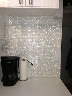 a coffee maker sitting on top of a counter next to a wall covered in sequins