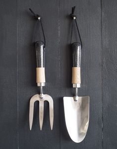 two metal utensils hang on the wall next to each other with wooden handles