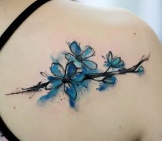 the back of a woman's shoulder with blue flowers painted on her upper arm