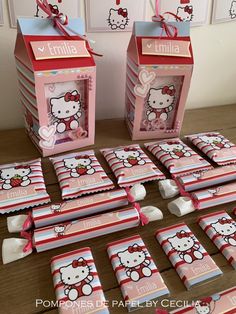 hello kitty candy bar wrappers are displayed on a table with pink and red boxes