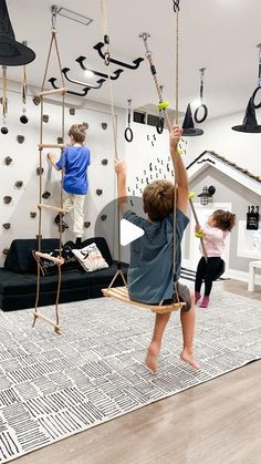 two children playing on swings in a playroom with black and white accessories hanging from the ceiling