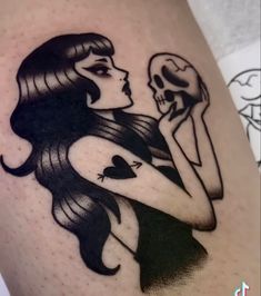 a woman holding a skull and wearing a black dress on her thigh with the word love written in it