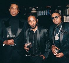 three men in tuxedos are posing for a photo with wine glasses on their hands