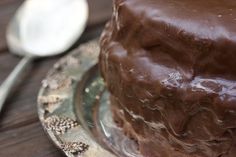 a chocolate cake sitting on top of a glass plate next to a spoon and fork