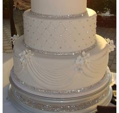 a three tiered wedding cake with white frosting and flowers on the bottom layer