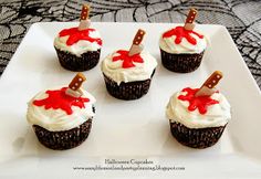 six cupcakes decorated with white frosting and red icing on a plate