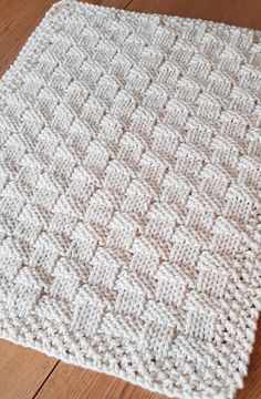 a white crocheted blanket sitting on top of a wooden floor