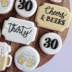 decorated cookies are arranged on a wooden platter with beer glasses and cheers and beers written on them