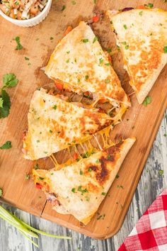 three quesadillas cut in half on a cutting board with a bowl of salsa