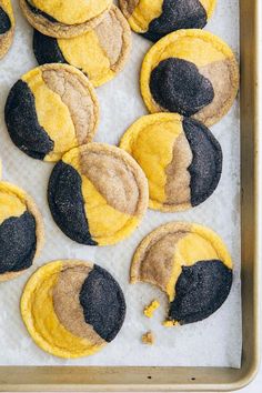 cookies with yellow and black frosting are on a baking sheet, ready to be baked