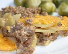 a white plate topped with meat and vegetables next to brussel sprouts