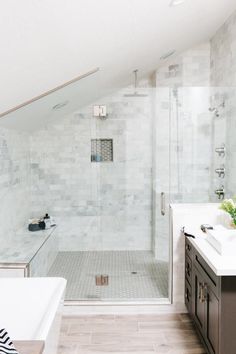 a bathroom with a walk in shower next to a bathtub and sink under a slanted ceiling