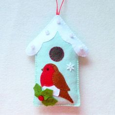 a birdhouse ornament hanging on a white wall with red and green decorations