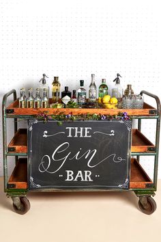 an old fashioned bar cart is decorated with bottles and glasses on wheels that read the gin bar