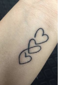 a heart tattoo on the wrist with two intertwined hearts