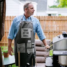 a man standing in front of an outdoor grill with the words king of the grill on it