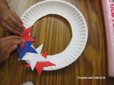 someone making a paper plate wreath with red, white and blue stars