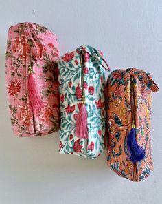 three bags with tassels hanging from the side, one in pink and one in blue