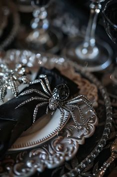 black and silver place settings with spider decorations on the plates, wine glasses and napkins