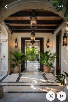 an entry way with potted plants and lights on either side of the entrance door