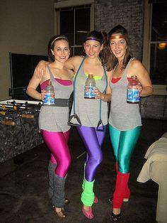 three women in colorful leggings and tank tops posing for the camera with cans of beer