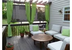 an outdoor deck with green curtains and white furniture