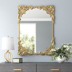 a large mirror sitting on top of a dresser next to a vase filled with flowers