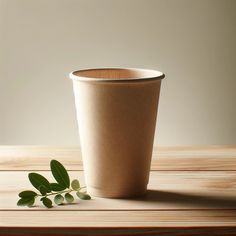 a paper cup sitting on top of a wooden table next to a leafy plant