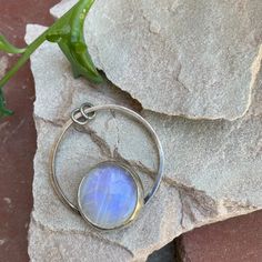 "Rainbow moonstone has always been one of my favorites, with its blue and purple flashes, and this stone is no exception, it's got a GORGEOUS flash. Moonstone is said to represent feminine power and hope, but is most commonly known to be the birthstone for those lucky enough to be born in June. A rainbow moonstone is set in a sterling and fine silver bezel. I cut the back of the bezel out because when the light hits it just right, she just glows. The stone sits on top of a circular base which has two jump rings that I left open so you can string it onto a necklace of your choosing. This one-of-a-kind pendant is approximately 1.5\" in diameter. Please note that this listing is for the pendant only; necklace is not included. This pendant is definitely a statement pendant, so I recommend pair Spiritual Moonstone Cabochon Ring, Bohemian Moonstone Jewelry With Moon Phase Detail, Bohemian Moonstone Jewelry With Moon Phase, Celestial Moonstone Jewelry With Natural Stones, Moonstone Jewelry With Moon Charm For Meditation, Mystical Moonstone Cabochon Ring, Mystical Moonstone Ring With Cabochon Cut, Mystical Cabochon Moonstone Ring, Moonstone Moon Charm Jewelry