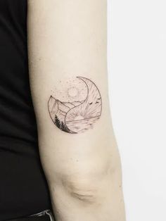 a woman's arm with a mountain and moon tattoo on the left inner arm