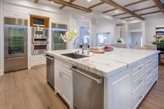 a large kitchen with an island in the middle and stainless steel appliances on both sides