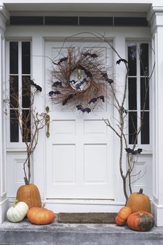 a white door with pumpkins and branches on it