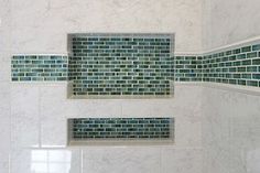 a white tiled shower with blue and green glass tiles on the wall next to it